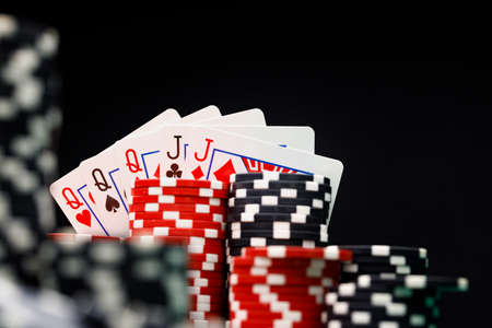 Poker chips and playing cards on black background