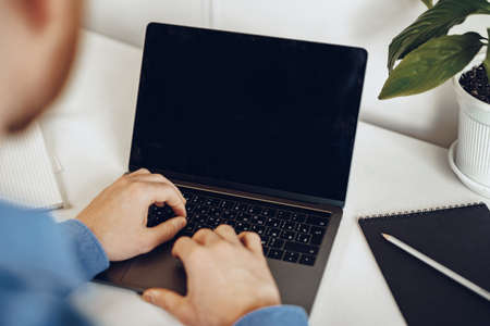 Close up of male hands typing on laptop with black screenの写真素材