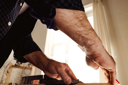 Carpenter makes pencil marks on a wood plank