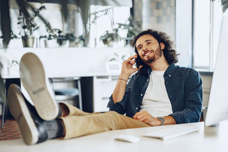 Casually dressed young businessman using mobile phone in officeの写真素材