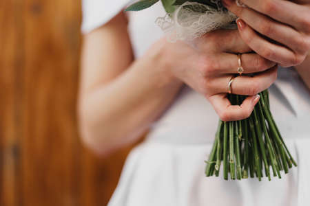 Unrecignizable bride in white dress holding bouquet close up