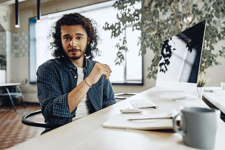 Attractive young handsome businessman sitting in office and talking to you