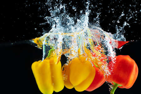 Bell pepper falling into water with a splash against black backgroundの写真素材