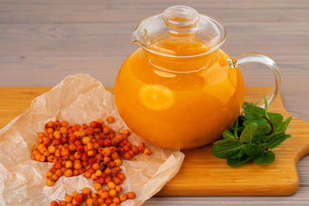 Glass teapot with .sea ââbuckthorn on wooden tableの写真素材