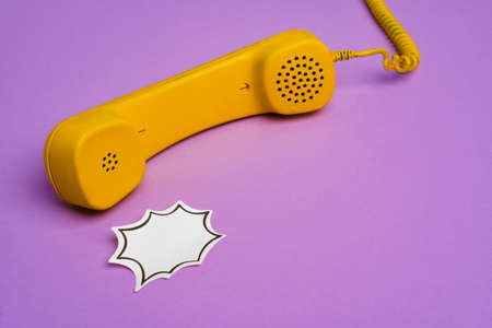 Yellow landline phone with speech bubble on purple backgroundの写真素材