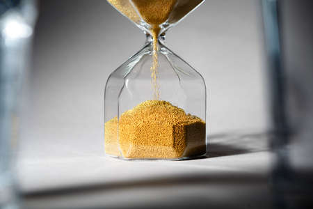 Hourglass with sand on gray background close upの写真素材