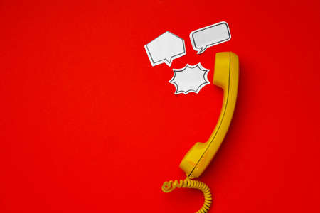 Yellow telephone speaker and speech bubble on red backgroundの写真素材