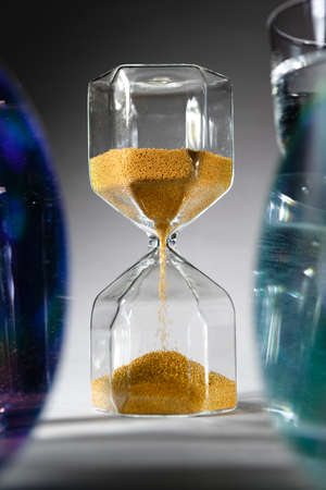 Hourglass with sand on gray background close up