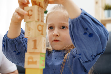 Little blonde girl playing wooden cubes at homeの写真素材