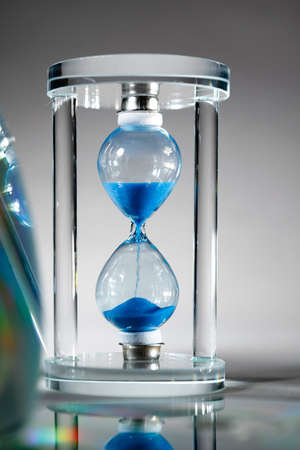 Blue hourglass on gray background close up