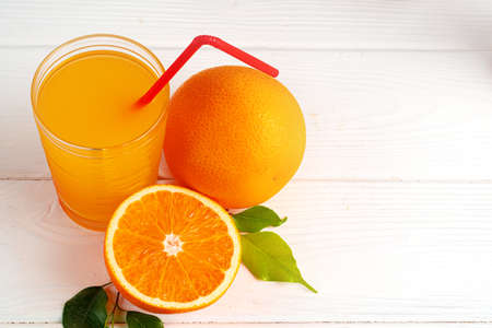Glass of orange juice with red straw on tableの写真素材