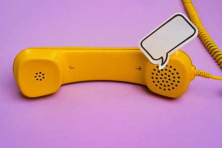 Yellow landline phone with speech bubble on purple backgroundの写真素材