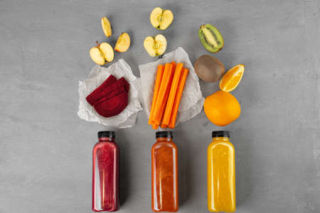 Three plastic bottles with freshly squeezed juice on gray backgroundの写真素材