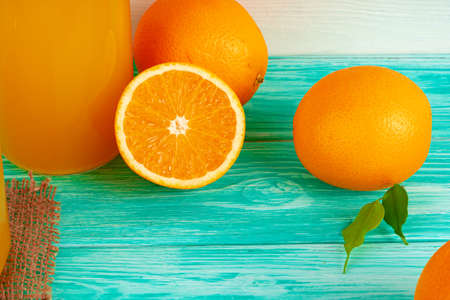 Glass of orange juice and cut oranges on table