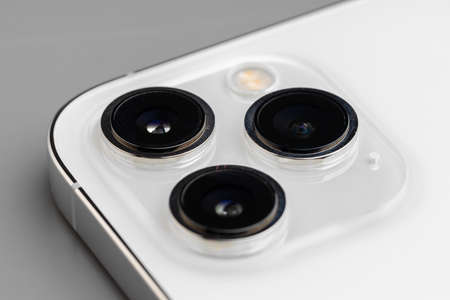 Close up of triple-lens camera of modern smartphone on gray background