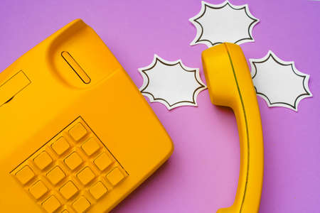 Yellow landline phone with speech bubble on purple background