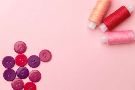 Multicolored thread spools and buttons on pink backgroundの写真素材