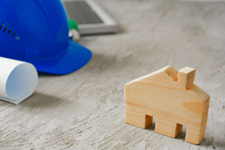 Wooden house miniature and blueprints on wooden table