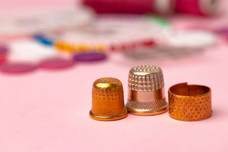 Iron thimbles for sewing on pink background