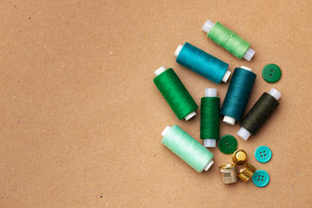 Thread spools and buttons on beige background