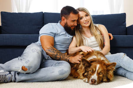 Young loving couple relaxing in living room with their dog pet