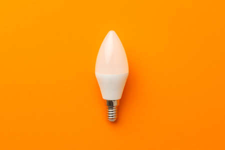 Light bulb on bright orange background top view