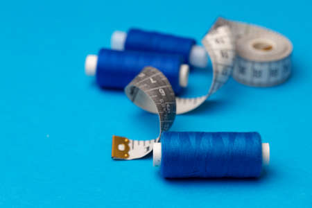 Thread spools and measuring tape on blue background
