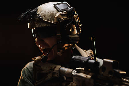 US special forces soldier looking at the aim ready to shoot against black dark backgroundの写真素材
