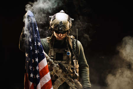 Special forces soldier holding US national flag in the darkの写真素材