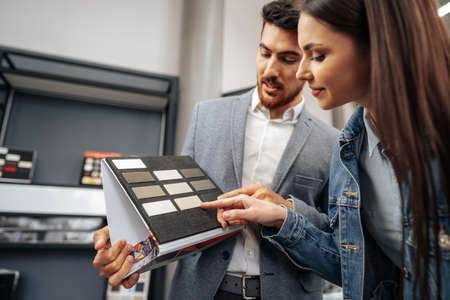 Salesman shows color swatches to lady customer for new kitchen furnitureの写真素材