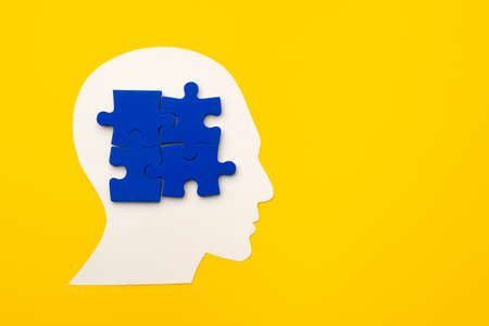 Papercut head silhouette with puzzle pieces on yellow backgroundの写真素材