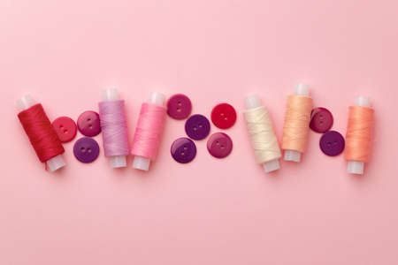 Multicolored thread spools and buttons on pink backgroundの写真素材
