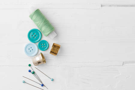 Colorful sewing accessories on white wooden table