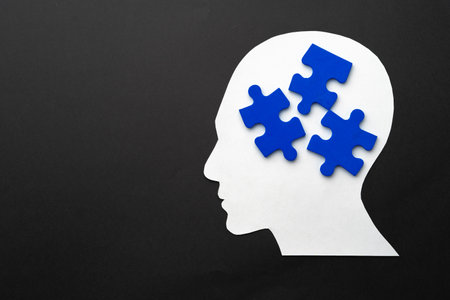 Papercut head with jigsaw puzzle pieces on black backgroundの写真素材