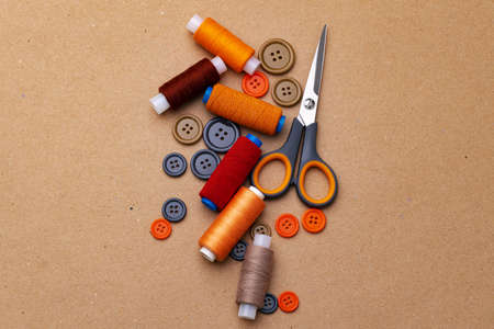 Sewing buttons and scissors on beige background