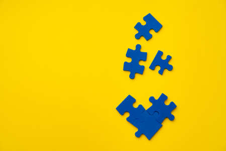 Blue puzzle pieces on paper background top viewの写真素材