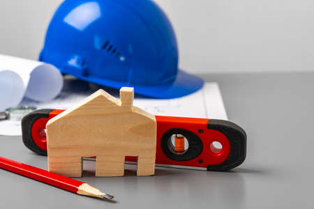 Wooden house model, blueprints and building level on gray deskの写真素材