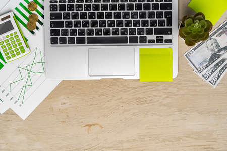 Top view of laptop and printed charts on office table