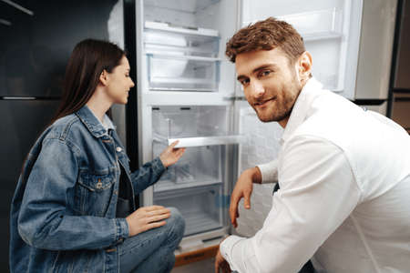 Young couple selecting new refrigerator in household appliance storeの写真素材