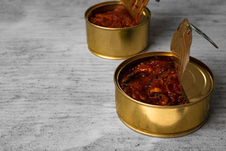 Open cans of canned fish on gray wooden tableの写真素材