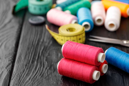 Colorful sewing utensils on black wooden surfaceの写真素材
