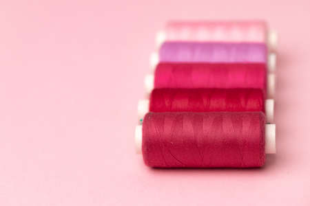 Set of threads spools on pink background