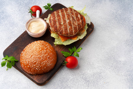 Fresh burger served on wooden board on gray surfaceの写真素材