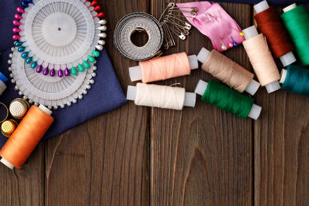 Threads and sewing accessories on brown wooden table