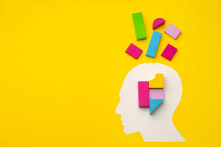 Papercut head silhouette with toy constructor pieces on yellow background