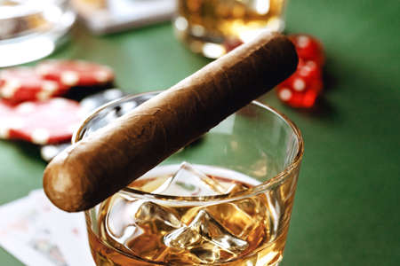 Cuban cigar, whiskey glass and chips on table