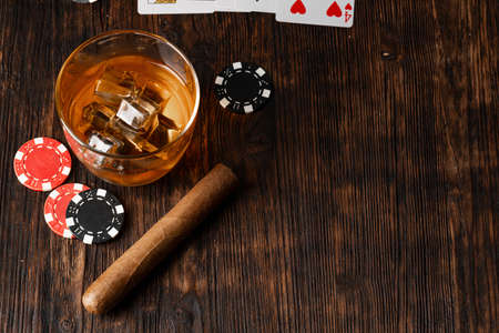 Cuban cigar, whiskey glass and chips on tableの写真素材