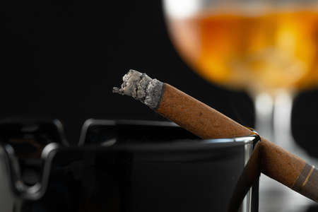 Close up of smoking cigar and whiskey glass on table