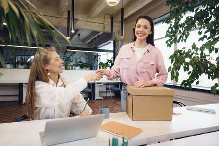 Young businesswoman holding box of personal belongings about to leave office after quitting jobの写真素材