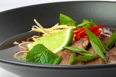 Asian soup with beef and udon noodles isolated on white